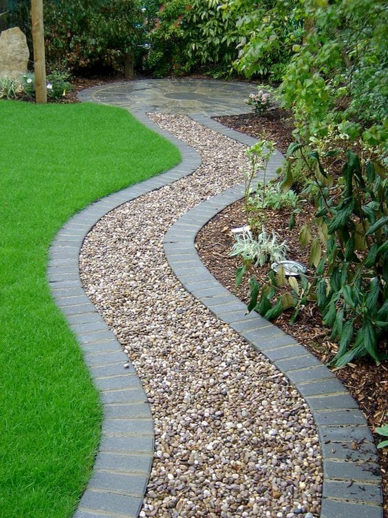 a gravel gardne path lined with bricks to keep gravel in place and make it look neat